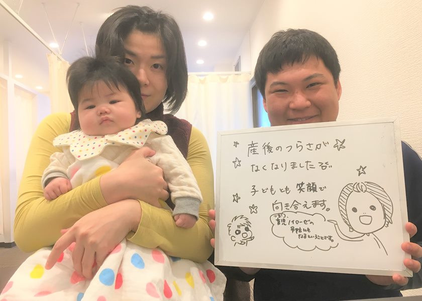 「産後のつらさがなくなりました 子どもとも笑顔で向き合えます」と書かれたボードと、お子さんを抱いた女性、院長のツーショット写真