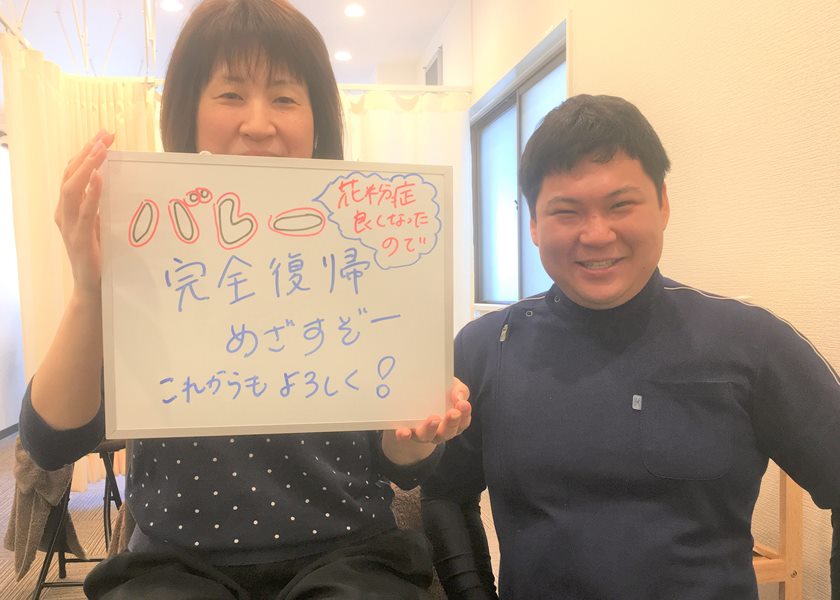 「バレー完全復帰めざすぞー」と書かれたボードを持つ女性と、院長のツーショット写真